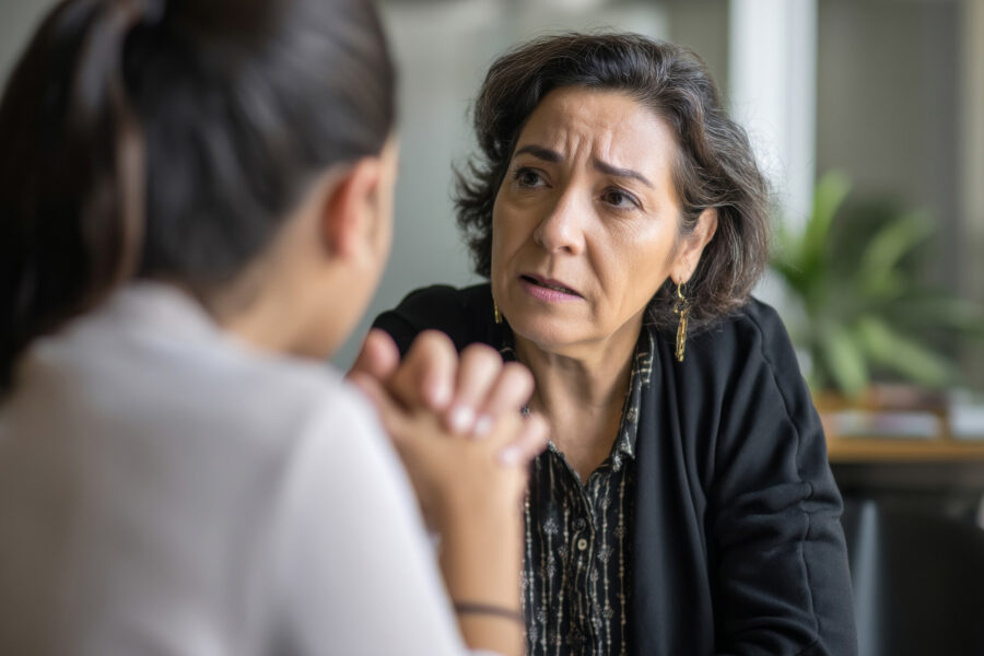 Woman listening intently to another woman representing a clinical supervisor in a one-to-one consultation session.